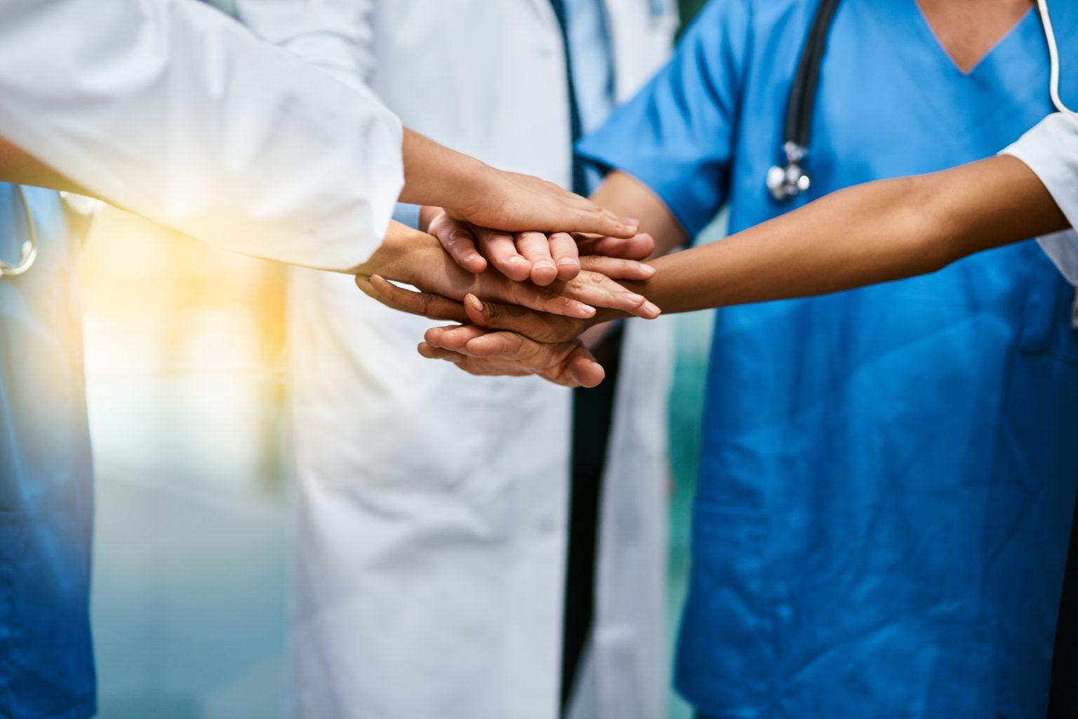 Shot of a group of unrecognisable medical practitioners joining their hands together in unity