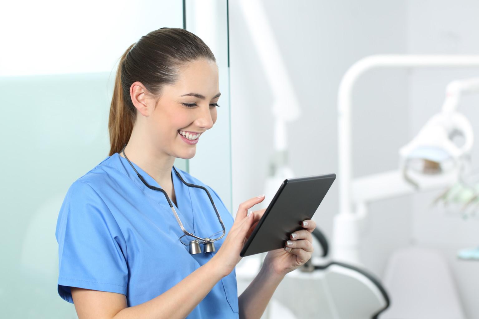 Happy dentist consulting online information in a tablet in a consultation